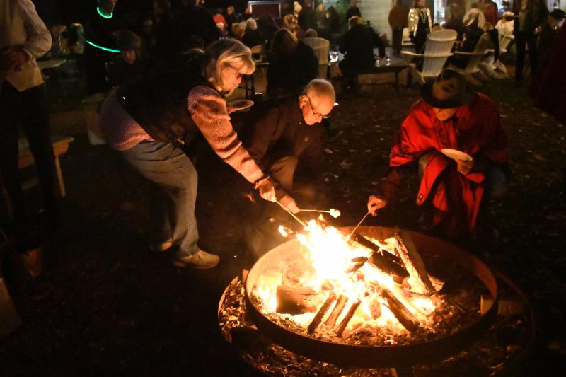 Gathering around the fire, Boos & Brews attendees use all the fixings provided by historical society volunteers to make s’mores.