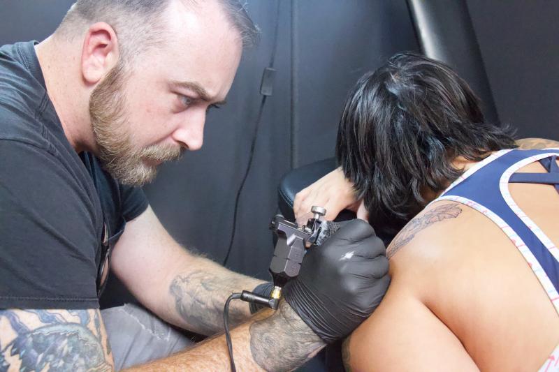 Carved Ink Studio artist and owner Ben Leadlove works on Helen Odenwald, who purchased a pumpkin tattoo to support the cause.
