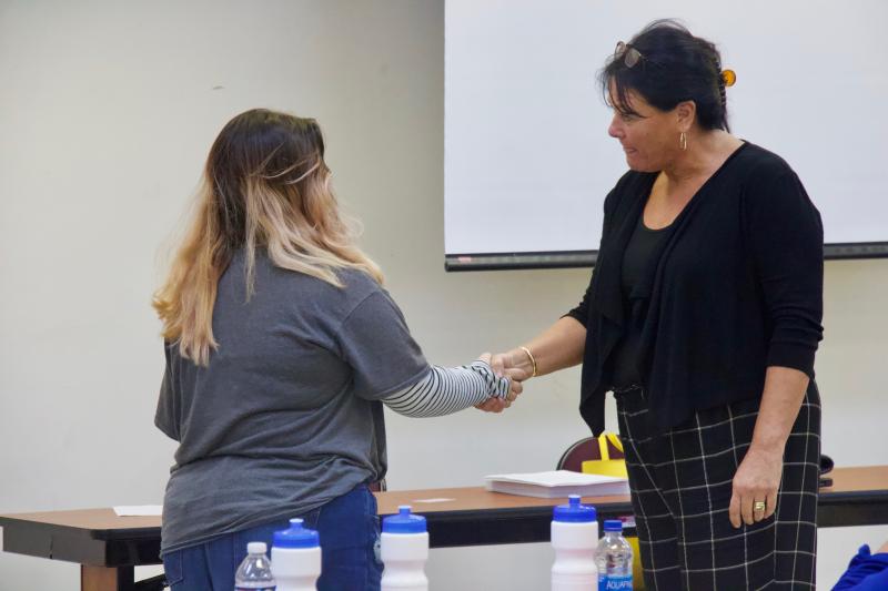 Alaina Neese delivers a firm handshake to academic coach Jennifer Thompson while making eye contact.