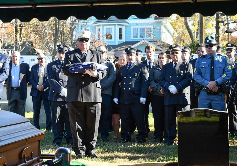 Rehoboth Beach Volunteer Fire Company Chief Chuck Snyder holds the folded flag from the casket of Danny Mitchell.