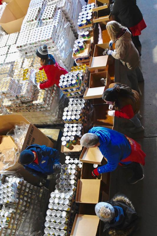 From above, volunteers move meal boxes along one of four assembly lines set up at Mountaire’s Selbyville plant.