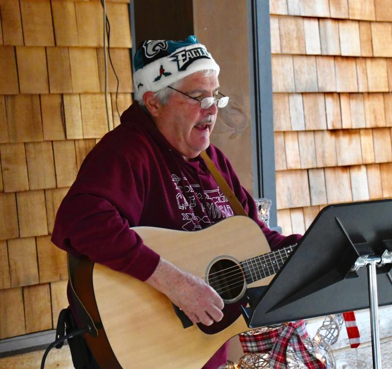 Walt Lafontaine, Camp Arrowhead executive director, strums his guitar and sings Christmas songs as children arrive.