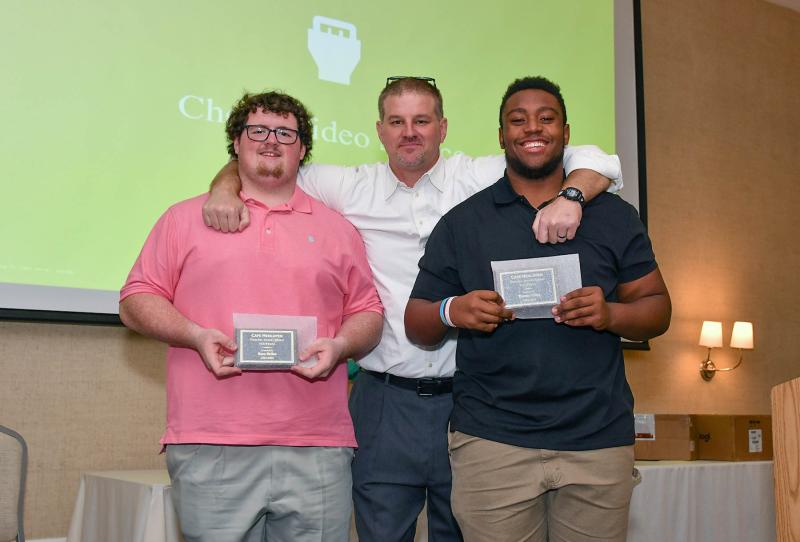 Ryan Betins, left, and Thomas Gibbs, right, receive the Offensive and Defensive Trenches Awards from head coach Mike Frederick.