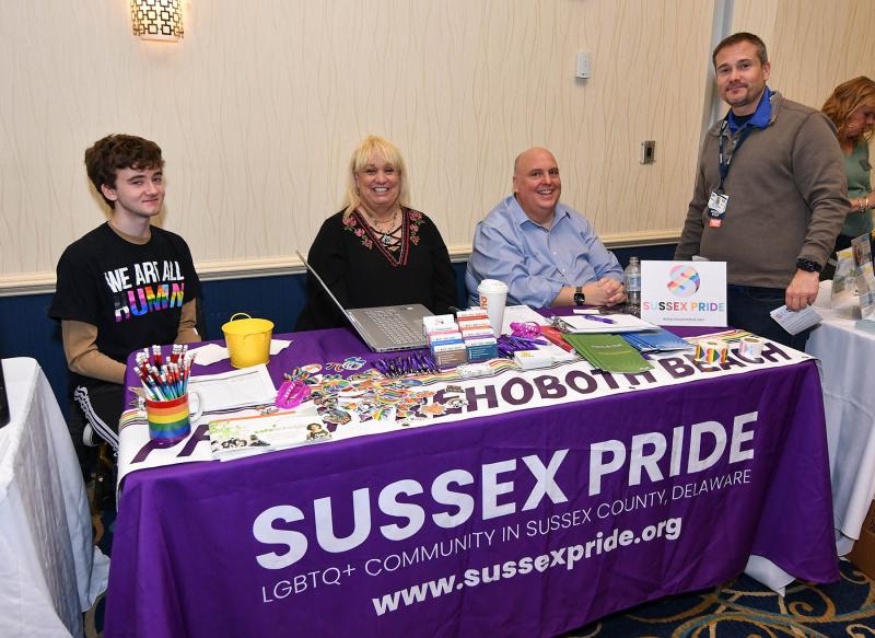 Working at the Sussex Pride table are (l-r) volunteer Jayden Taylor, board member Kathy Carpenter Brown, Executive Director David Mariner. Visiting the table is Dr. Bill Chasanov.