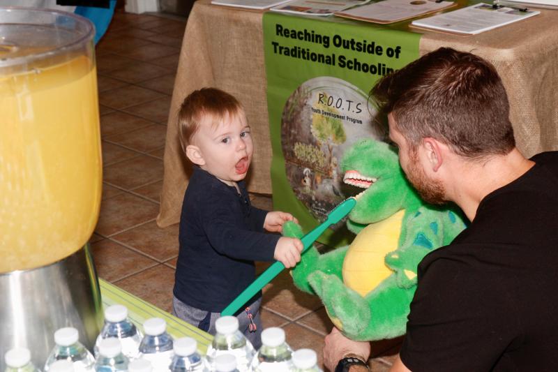 Like father, like son. Jack Roach brushes the teeth of the stuffed dinosaur his dad Zach Roach is holding. Zach is a dentist with The Dental Group in Lewes.
