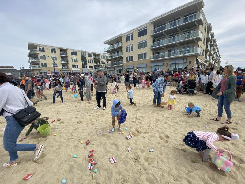 Children scour the sand for eggs while parents take photos at the 2022 Dewey Egg Scoop. ELLEN DRISCOLL PHOTO