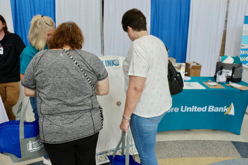 Shore United Bank’s Ronda Douglas invites Donna Feister, left, and Rosanne Grandon to play a game of Plinko.