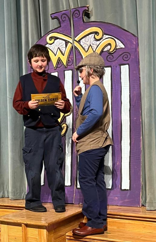 Ethan Baranowski as Charlie, left, shows his golden ticket to Adrian Santiago, portraying Grandpa Joe.