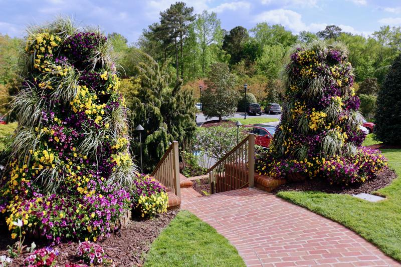 Greeting golfers and clubhouse patrons coming from the parking lot are two columns of purple and yellow flowers mixed in with greenery.