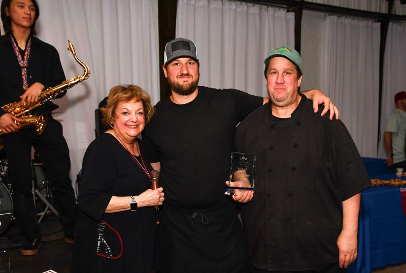 Meals on Wheels Event Chair Lana O'Hollaren presents the second-place award to chef Ryan Steele and chef/owner Richard Steele of Cafe Azafran for their paella cakes.