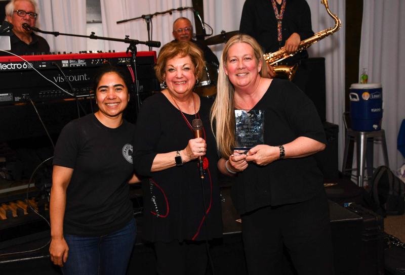 Meals on Wheels Event Chair Lana O'Hollaren presents the top dessert award to Backyard owner Ami Rae, right, and helper Meylin Sanchez for their tres leches cake.