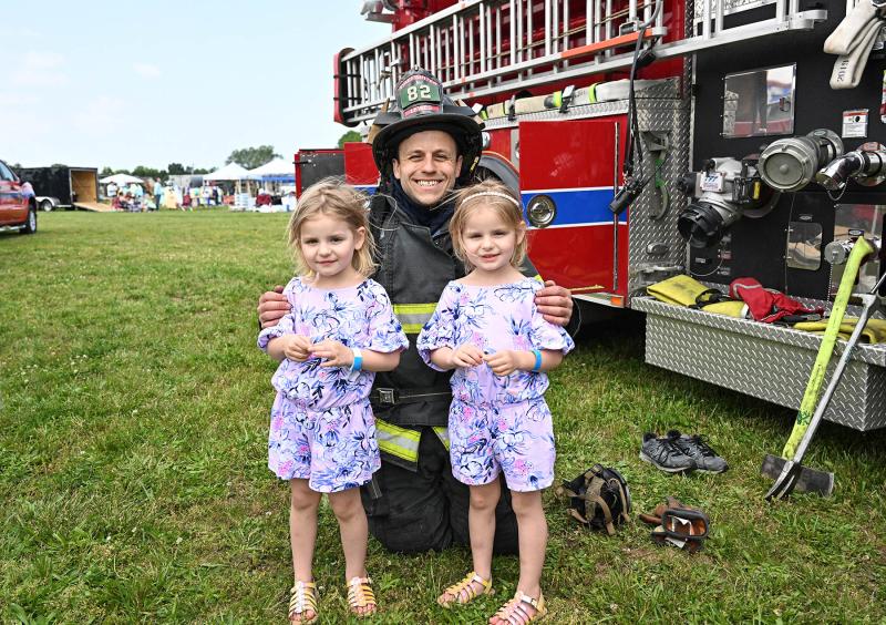 Joe Esposito of the Lewes Fire Department shows his firefighting equipment to 4-year-old twins Lily and Daisey Bobb.
