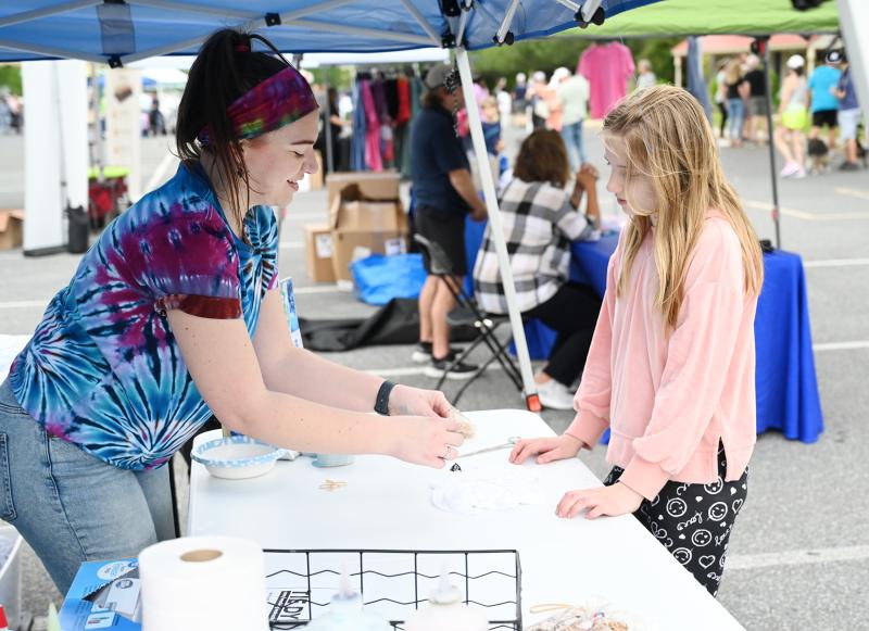 Abby Workman of D. Beach Tie-Dye teaches Romy Calloway, 10, of Ellendale how to make a tie-dye shirt.