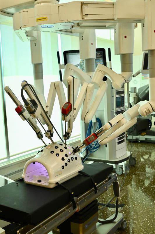 The arms of the da Vinci Xi surgical robot are maneuvered by a surgeon sitting at a pod with joystick-like controls.