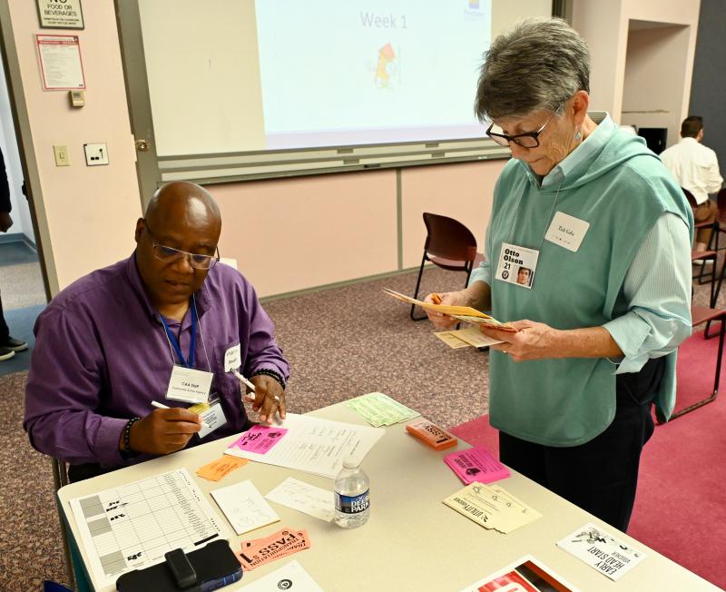 Social worker Stanley Powell of First State has all of the cards and vouchers the families will need. Obtaining transportation passes is Tish Galu aka “Otto.”