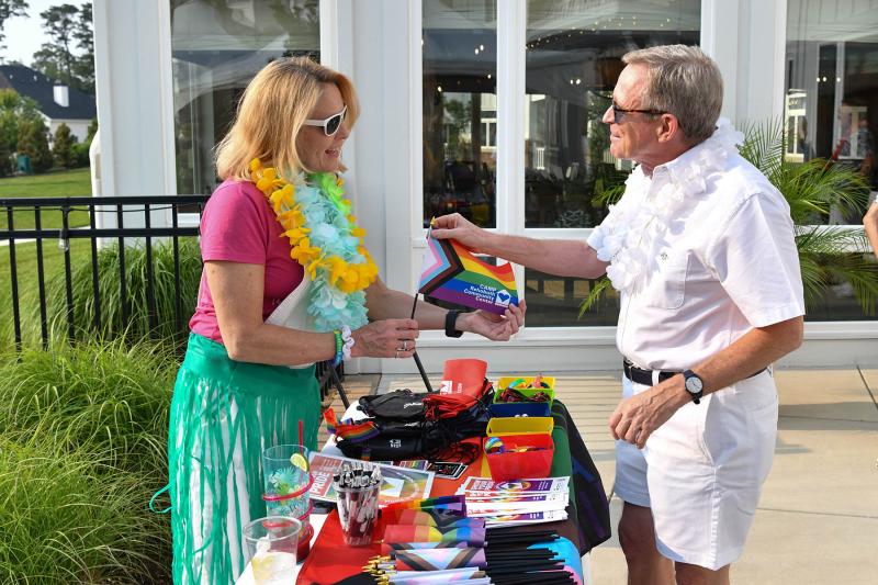 Patrick Everett, right, takes a CAMP flag from Tara Sheldon, health and fitness manager at CAMP Rehoboth.