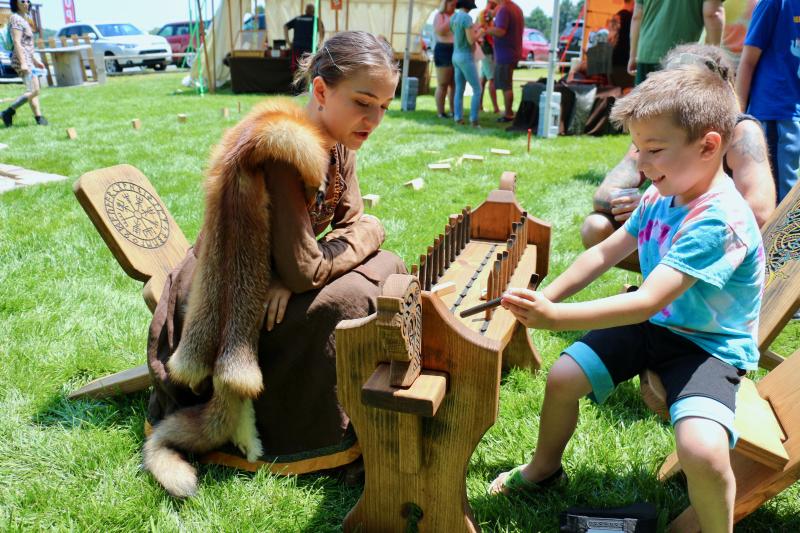 After Jaelyn Buchholz, left, taught Thomas Troescher, 6, how to play a new board game, the little guy quickly starts to pillage and plunder his former teacher as proud papa Brandon Roach looks on. AARON MUSHRUSH PHOTO