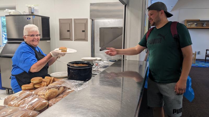 Shirley Fleegle, a devoted member of Lutheran Church of Our Savior, serves up a sloppy joe to Stephen Luchita, who is from Romania.