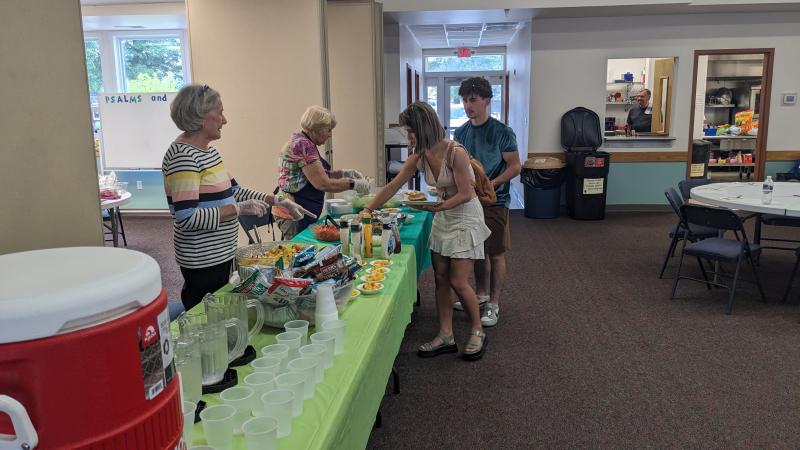 Romanians Serah Pandelea, front, and Abel Pandelea grab a salad to go with their sloppy joe before scooping a few bowls of fresh fruit salad at Lutheran Church of Our Savior.