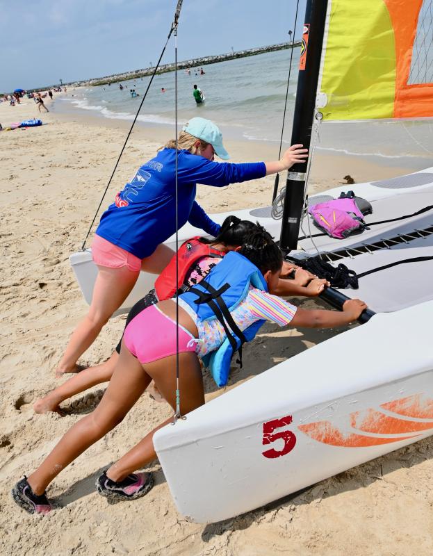 LYC sailing instructor Tatum Carney gets some help from Valentina Pelico, left, and Nyla Alford as they launch a Hobie.