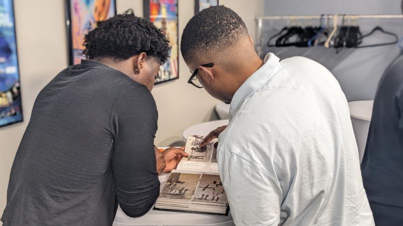 Bryce Daisey, left, and his brother Cameron Daisey peruse a family album on display in the theater lobby. Their dad, Darnell, came over and identified people and their relationship to the young Daisey duo.