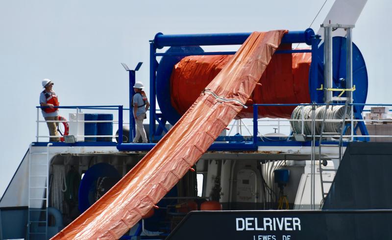 Some of the more than 3,000 feet of oil-containment boom is offloaded from a large spool on the DelRiver. The entire length can be deployed in 15 minutes.