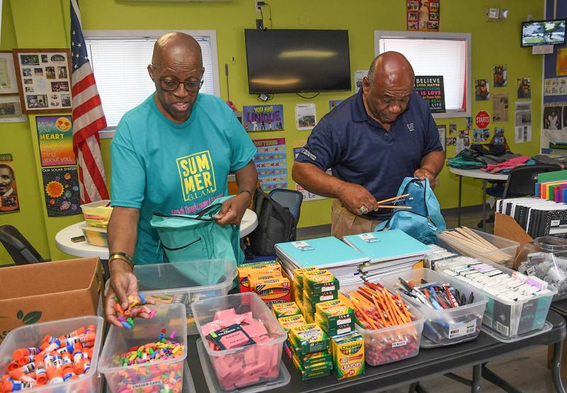 West Side New Beginnings co-founder Diaz Bonville, left, and community supporter Bill Collick stuff backpacks with supplies.