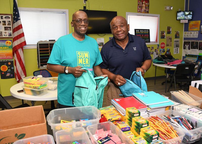 West Side New Beginnings co-founder Diaz Bonville, left, and community supporter Bill Collick smile as they prepare to give out backpacks.