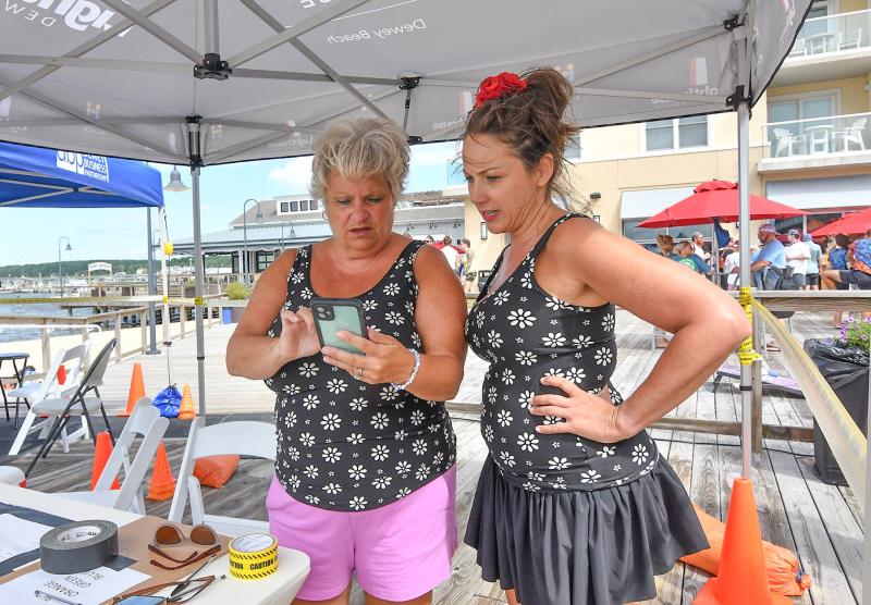 Volunteer Bobbie Redefer, left, and Dewey Business Partnership Executive Director Kelly Ranier review rules on their phone.
