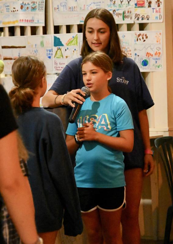 Campers are responsible each day for leading chapel services. In the photo, counselor Abby Forget holds the microphone for Brianne Cross as they perform a skit.