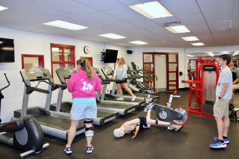 This scenario of a man collapsing while on a workout bike simulated something that happened in real life. The trainers are acting as bystanders emulating how bystanders can make rendering care more difficult.