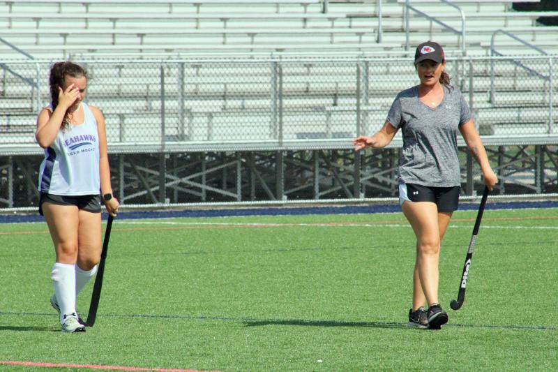 Coach Leah Hunsinger, left, uses junior defender Madison Jones to demonstrate why it is important the girls shake off their defender and find open space to receive a pass and continue the offense.