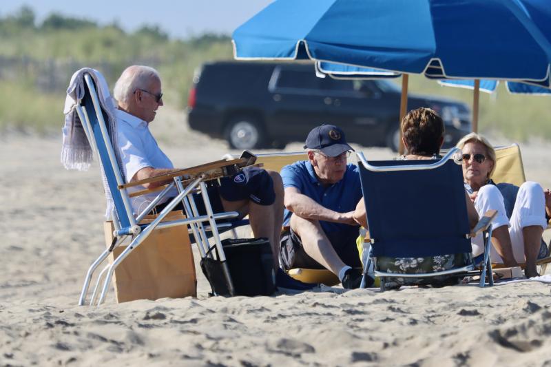The president and first lady relax with friends on the beach. The president has a Beau Biden Foundation baseball cap on his knee.