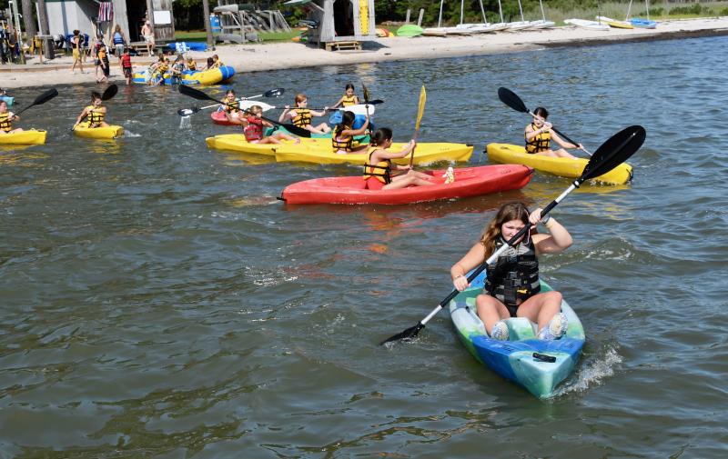 Spending time on Rehoboth Bay, which borders Camp Arrowhead, is a big part of the busy schedule of activities. A large group leaves the shore to paddle kayaks.