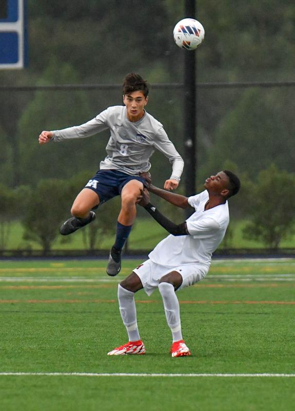 Sussex Academy junior Aiden Villar gets big air to head the ball away from Milford’s Freedly Napoleon.