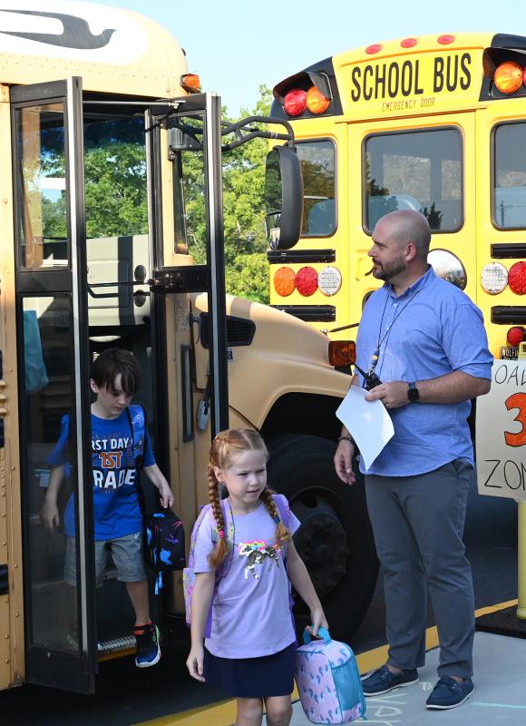 Assistant Principal Jason Scott helps young students off the bus at Milton Elementary. NICK ROTH PHOTO