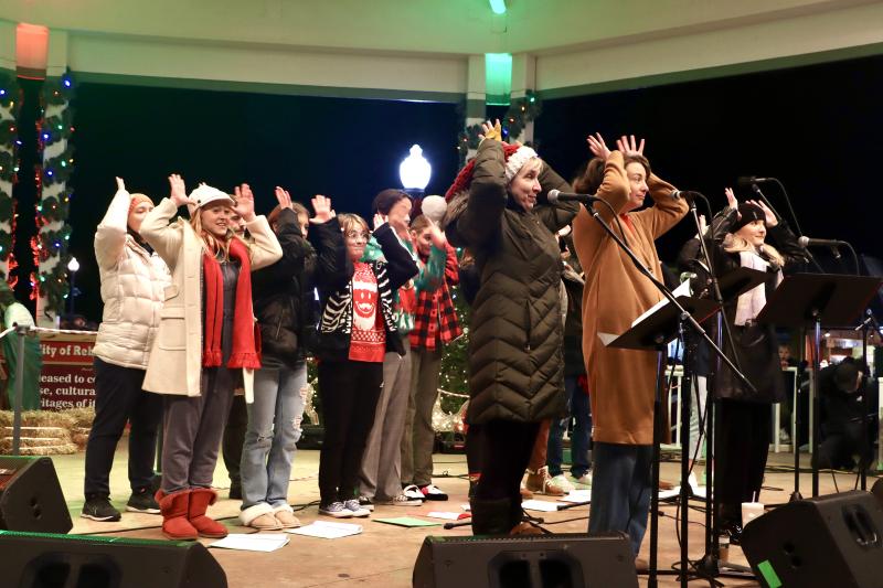 Performers from Clear Space Theatre Company lead the crowd in a Christmas carol sing-along at the tree lighting ceremony.
