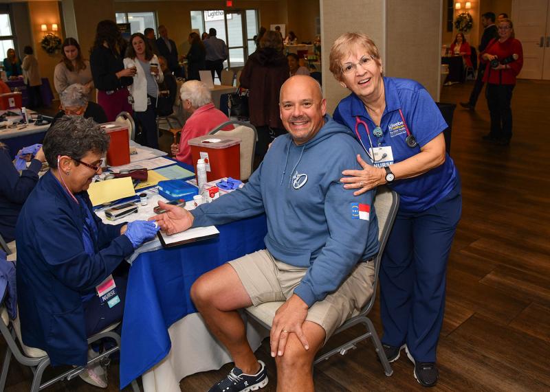 Kevin Summerville, center, gets support from his mother Mary as Beebe Healthcare nurse Edna Glassman Lackow performs cholesterol and glucose testing.