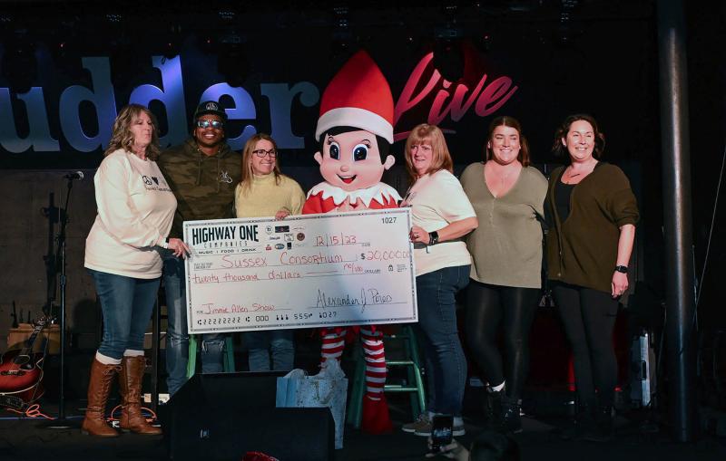 Jimmie Allen and Highway One Companies present $20,000 to Sussex Consortium staff and administration. Shown are (l-r) Consortium staff member Lisa Thorp, Allen, Principal Vivian Bush, Elf on the Shelf, Consortium staff member Jackie Dorney and Bottle & Cork managers Brianna Sullivan and Kathleen Roberts.