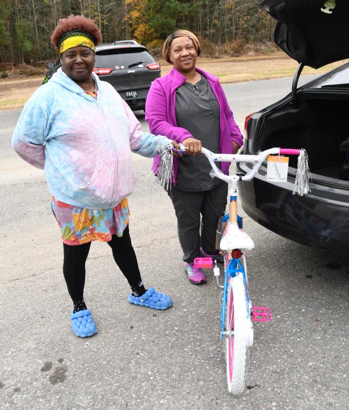 Volunteer Sherne Perry, left, helps Quayshetta Hopkins load a bicycle to be a young girl’s Christmas present this year.