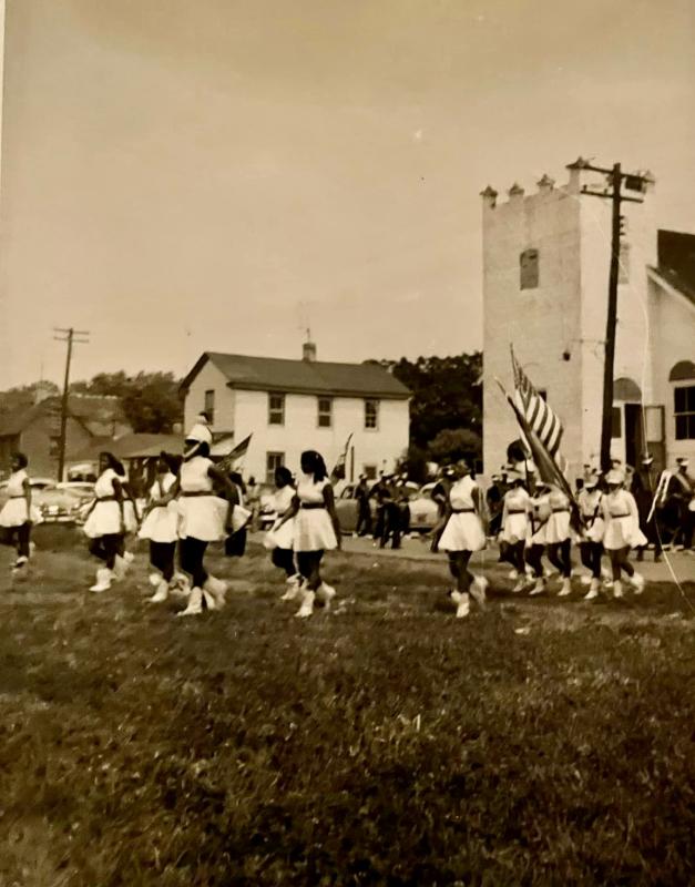 Unidentified majorettes/color guards march onto Shipcarpenter Square. St. George’s AME Church is in the background. SOURCE: DAISEY FAMILY LEGACY COLLECTION