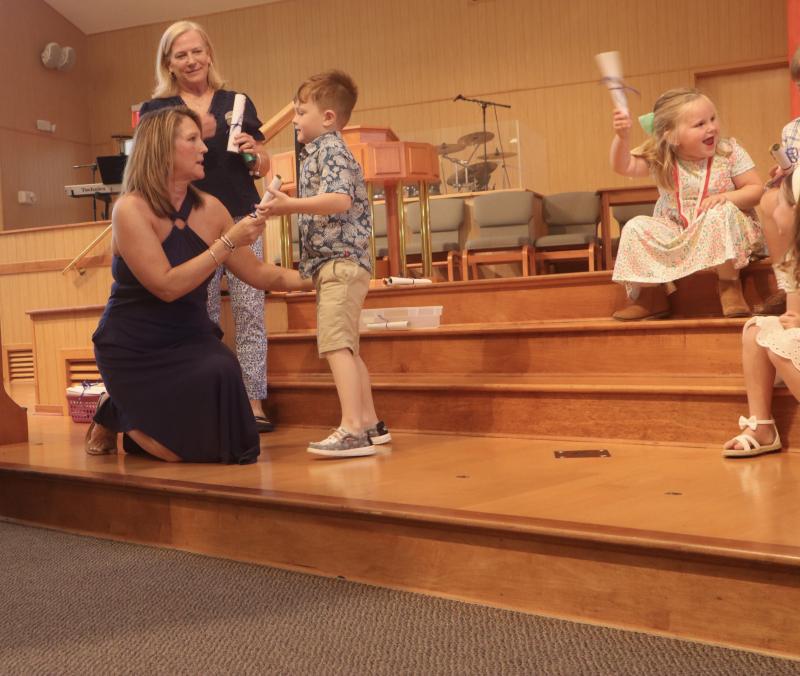 Teacher Carrie Dare hands Pelican Class graduate Bryson Day his diploma. Fellow Pelican Class graduate Emery Taylor expresses her excitement.