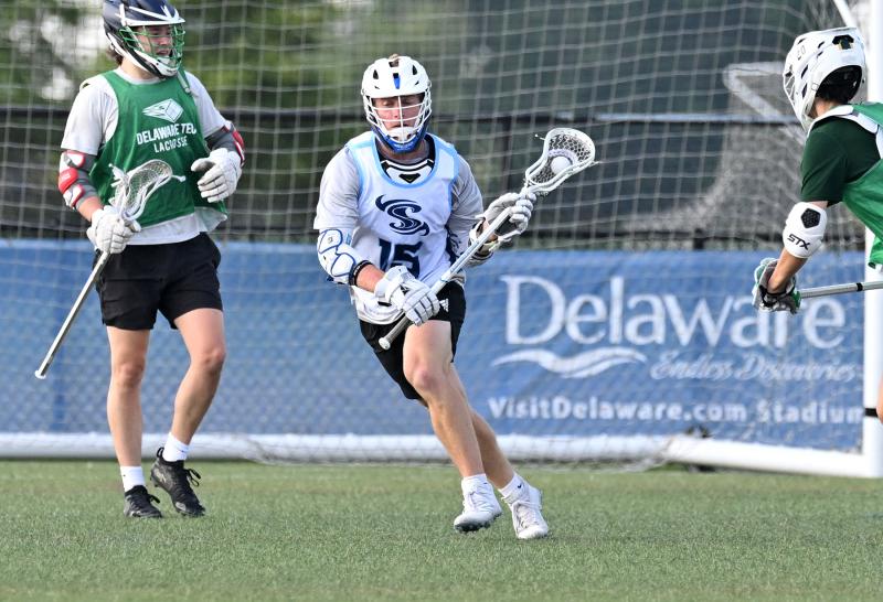Shorebreak Lacrosse middie Blake Gipko (Elizabethtown University) splits two Flaming Windows players as he clears the ball into Shorebreak’s offensive zone.