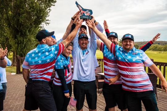Circled by his teammates, Austin Ebersole hoists the trophy as Team USA FlingGolf celebrates as the first winners of Britain’s Cup. Shown are (l-r) Ken Pytluk, Britt Hammond, Ebersole, Sam Scannell, Jake Anderson and Titus Harter. SUBMITTED PHOTO