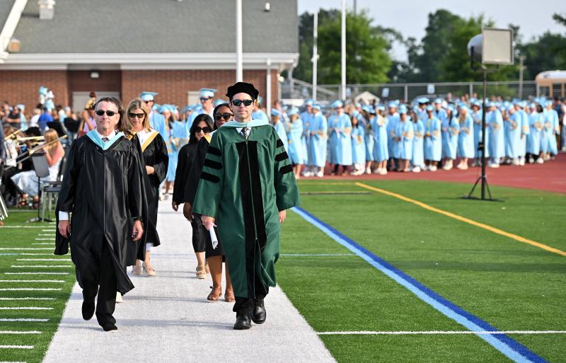 Guidance counselors Chris Mattioni, left, and Dr. Joel Simon lead the graduates onto the Legends Stadium turf for the commencement.