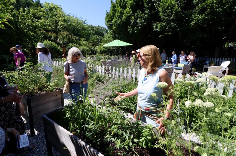 Amy Marasco tells a garden tour visitor how she planted the carrots in her raised vegetable and herb garden.