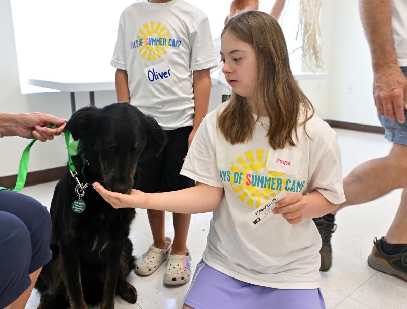 Paige Quann enjoys time with Marley, a canine from PAWS for People, which brought dogs for the campers to experience and enjoy their companionship.