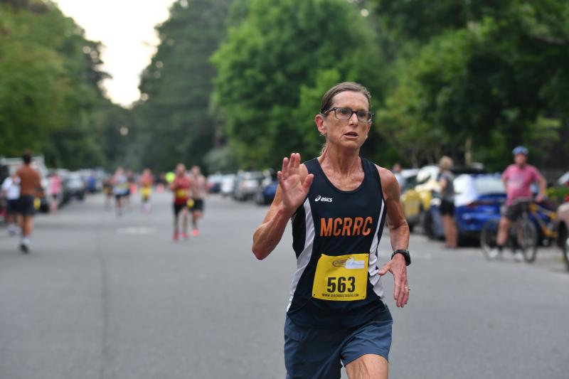 Cindy Conant either waves or says “no photos, please,” as she crosses the finish in 20:23.