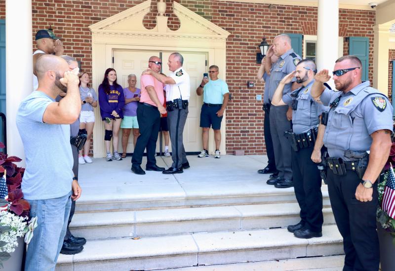 Lewes Police Chief Tom Spell, right, embraces Cpl. Chatham Marsch as fellow officers salute. Members of Marsch’s family are in the background. Marsch’s final day was July 5. He is joining the Delaware State Fire Marshal’s office as an investigator, after 19 years as a Lewes police officer. BILL SHULL PHOTOS