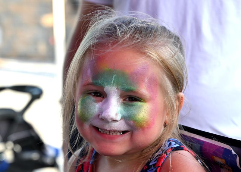 Arianna Flickinger, 5, smiles as she’s midway through a transition to a rainbow tiger with a little help from Penny Carroll of Canvas on the Move.
